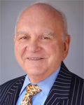 portrait of norm peters in a dark blue pin-stripe suit, pale blue shirt and gold patterned tie