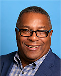 portrait of robert lewis in a medium blue suit with a blue and white checked shirt