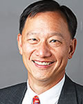 portrait of charles wu in a dark suit, white shirt and a red tie